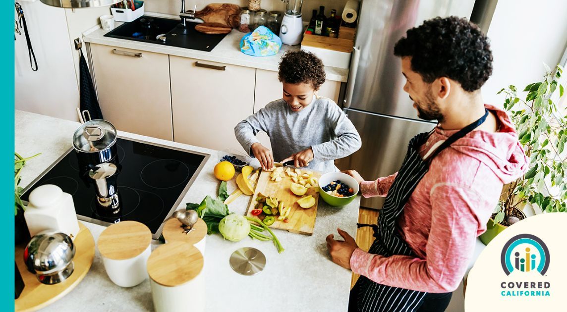 A dad and his son make a healthy meal together at home.